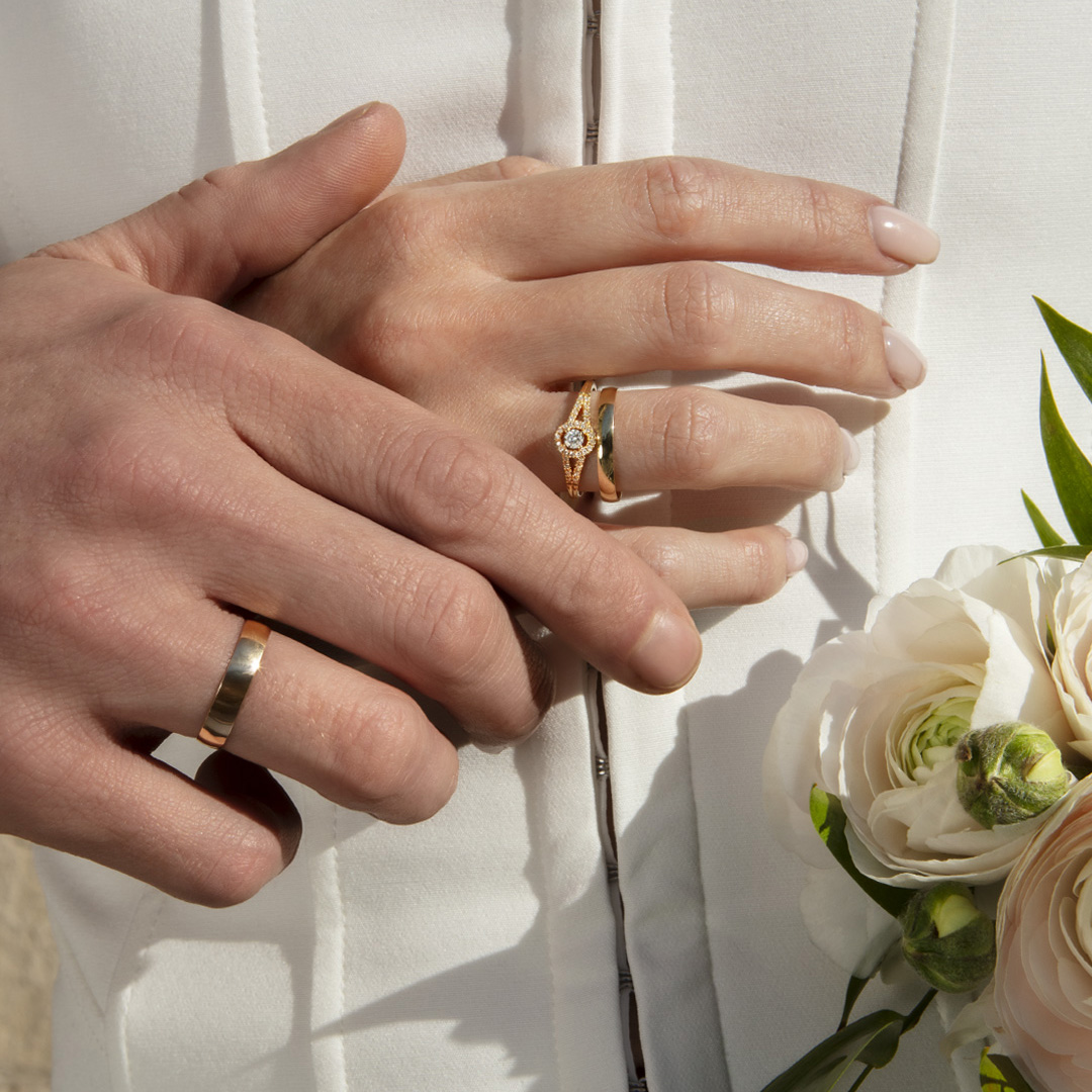 Alliances en or jaune sur des mains d'homme et de femme le jour du mariage