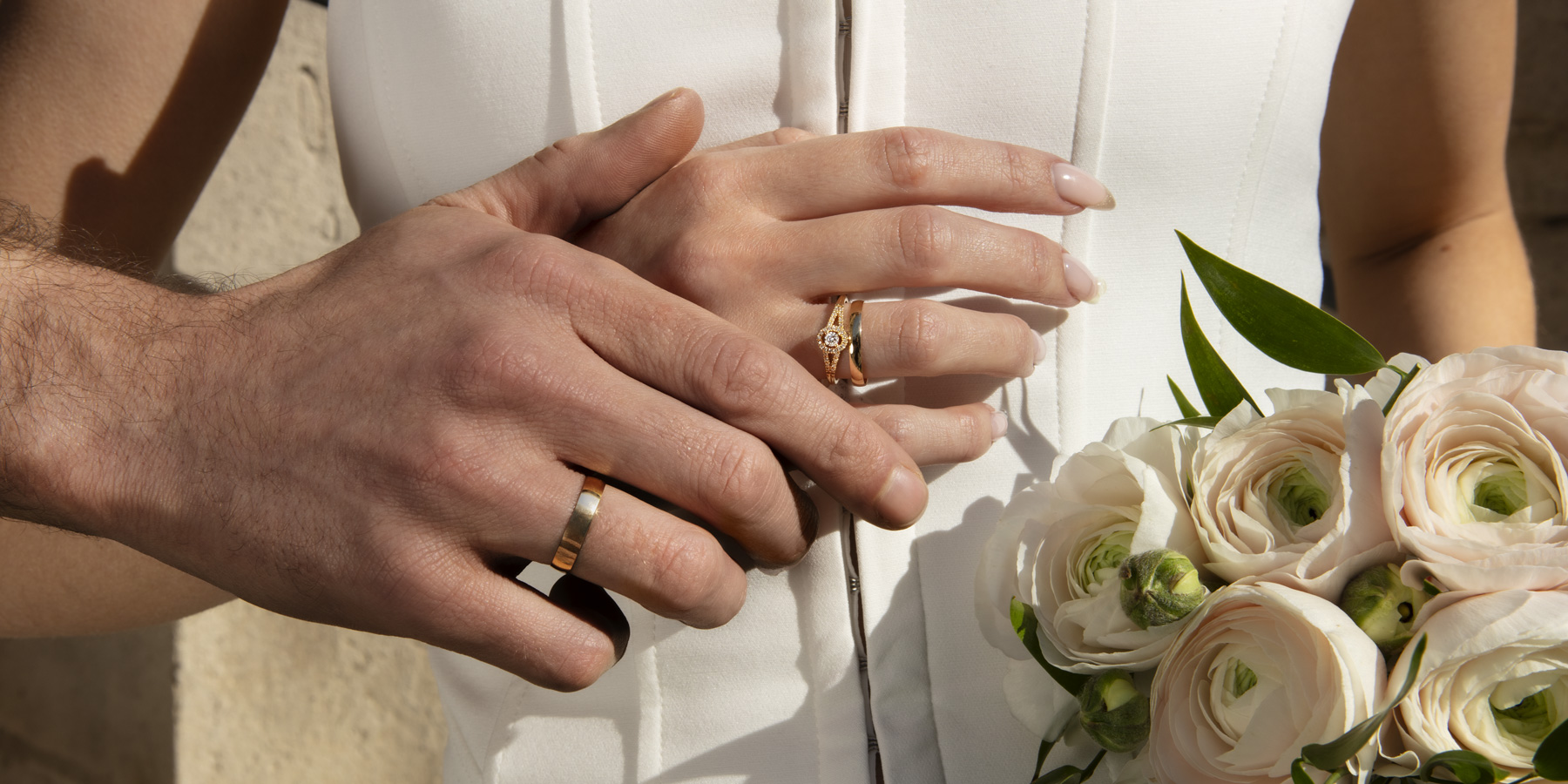 Alliances en or jaune sur des mains d'homme et de femme le jour du mariage