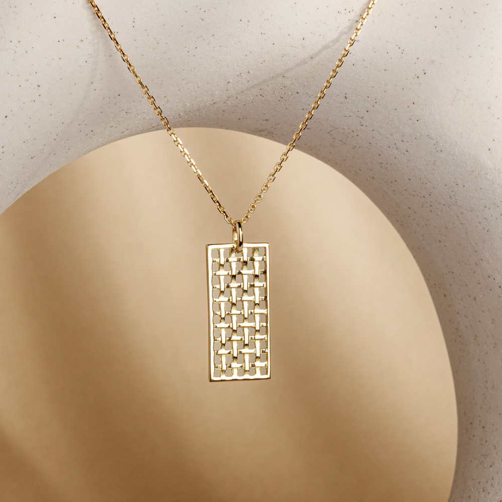 Bracelet, boucles d'oreille et collier Galerie Rue de Seine en or jaune avec plaque tissée de fils d'or portés par une mannequin